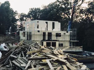 Unvollendetes Wohnhaus mit Baugerüst und Holzstapel — Symbolbild für Bauträgerinsolvenz und Baustopp