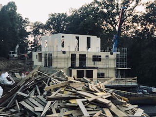 Unvollendetes Wohnhaus mit Baugerüst und Holzstapel — Symbolbild für Bauträgerinsolvenz und Baustopp